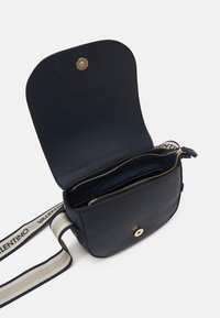 Granatowa skórzana torebka na ramię z magnetycznym zapięciem, wyposażona w zamykane na zamek wnętrze, złote dodatki i paskiem z paskiem w paski.