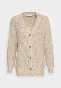 Stickad kofta i krämfärg med V-ringning, långa ärmar och fem stora bruna knappar fram. Texturerad med subtila prickar.