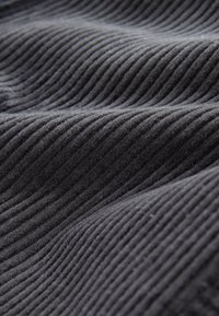 Tissu de velours côtelé gris foncé avec une texture rayée parallèle, présentant de fines crêtes et une surface douce et moelleuse. Idéal pour les vêtements ou le rembourrage.