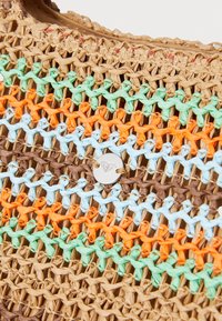 Woven bag with natural straw base featuring vibrant horizontal stripes in orange, blue, green, and brown. Metal logo accent in the center.