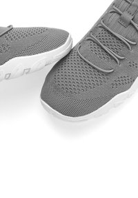 Graue Sportschuhe mit einem Mesh-Obermaterial, das ein strukturiertes Muster aufweist, und einer weißen Gummisohle. Enthält elastische Schnürsenkel für einen sicheren Sitz.
