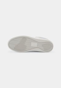 Shoe outsole in light gray rubber, featuring a herringbone tread pattern and textured accents. Flat design with smooth edges.