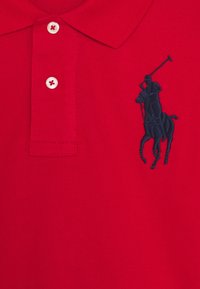 Rode polo shirt van textiel met een structuur, voorzien van drie witte knopen en een marineblauw geborduurd paard en ruiter logo.