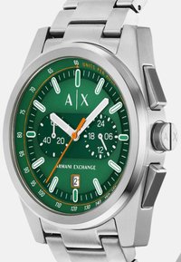 Ura iz nerjavečega jekla z zelenim izborom, belimi in oranžnimi akcenti, sub-diali za čas in prikaz datuma. Ima dizajn zapestnice s povezavami.