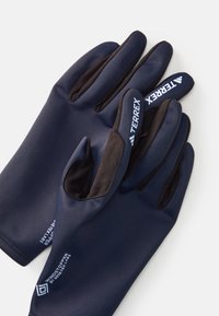 Mornarski rukavice s crnim vrhovima prstiju, izrađene od glatkog, fleksibilnog materijala. Sadrže detalje s logotipima, uključujući oznake "TERREX" i "WINDSTOPPER".
