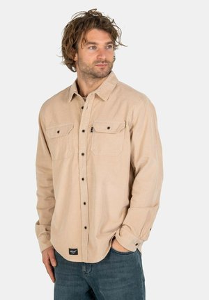 Beige Hemd mit Knopfleiste und langen Ärmeln, zwei Brusttaschen mit Klappen und kontrastierenden schwarzen Knöpfen, aus einem strukturierten Stoff gefertigt.