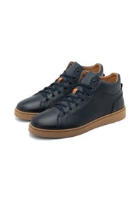 Une paire de baskets montantes en cuir bleu marine avec des semelles et des lacets marron, présentant de petites accents rayés orange et jaune sur les languettes.