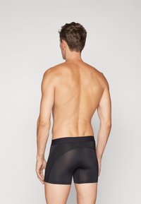 Black boxer briefs with a smooth texture, featuring a wide waistband and a fitted design, seen from the back.