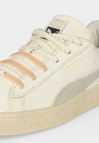 Ανοιχτόχρωνα σουέντ αθλητικά Puma με πλεγμένα κορδόνια, τρεις θηλιές κορδονιών σε ροδακινί χρώμα και υφασμένο λεπτομερές σόλας.