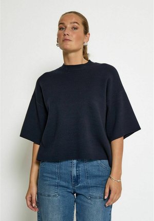 Navy cropped sweater with a round neckline and wide short sleeves, made from a smooth, lightweight fabric. Paired with high-waisted jeans.