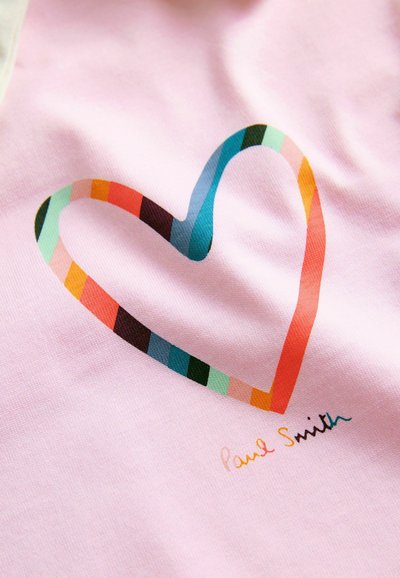 Cœur rayé multicolore imprimé sur un tissu rose avec un petit texte multicolore "Paul Smith" sous le cœur.