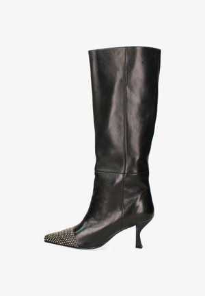 Botte en cuir noir, arrivant au genou, avec un bout pointu et des accents cloutés sur le cap de la chaussure, dotée d'un talon fin et d'une texture lisse.