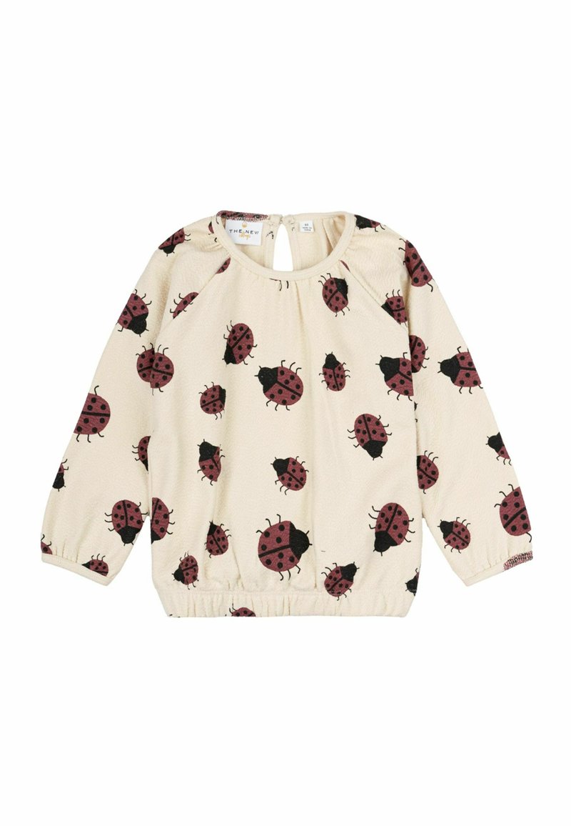 Maglietta a maniche lunghe color crema con orlo elastico, caratterizzata da un motivo di coccinelle nere e borgogna. Il dettaglio con apertura a chiave sul retro arricchisce il design.