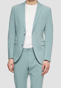 Licht turquoise pak met een gestructureerde afwerking, bestaande uit een enkeknoopscolbert met twee knopen en een insnijding in de revers, gecombineerd met bijpassende broek.