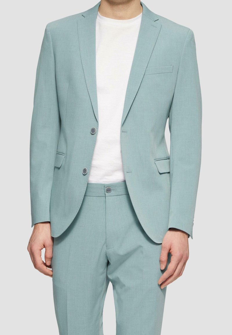 Licht turquoise pak met een gestructureerde afwerking, bestaande uit een enkeknoopscolbert met twee knopen en een insnijding in de revers, gecombineerd met bijpassende broek.