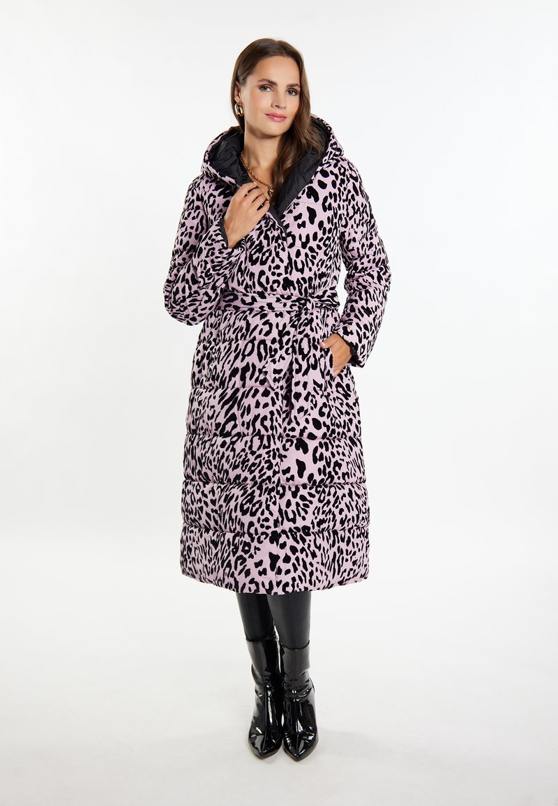 Puffjakke i leopardmønster i pink og sort med hætte, bælte i taljen og kviltet tekstur. Båret over sorte leggings og blanke støvler.