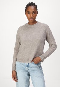 Lichtgrijze, zachte gebreide trui met een ronde hals en geribbelde manchetten, gecombineerd met losse lichtblauwe jeans.