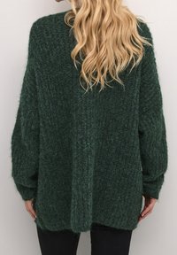 Oversized, mörkgrön tröja i ett strukturerat stickat material. Har sänkta axlar, långa ärmar och en rak fåll, som ger en avslappnad passform.