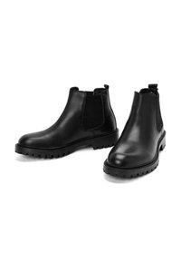 Stivali alla caviglia in pelle nera con pannelli laterali in elastico, punta rotonda, superficie testurizzata e suola in gomma robusta. Design minimalista, versatile per varie occasioni.