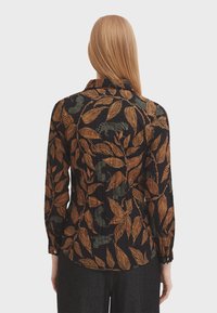 Black long-sleeve shirt featuring an orange and green leaf pattern. It has a collar and a slightly fitted design with button details.