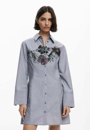 Abito camicia grigio con bottoni, caratterizzato da ricami floreali sulla parte anteriore, maniche lunghe con ampie polsini, realizzato in un tessuto morbido.