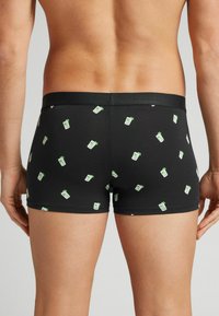 Černé boxerky s potiskem malých zelených mátových listů a pohárů na nápoje. Vyrobené z pružného materiálu, s měkkým pasem.