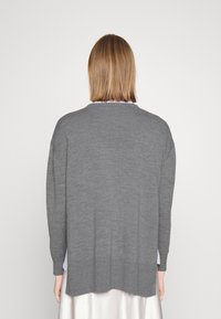 Grauer übergroßer Pullover mit gerippter Textur, lockerer Passform und längerer hinterer Partie. Mit langen Ärmeln und Rundhalsausschnitt.