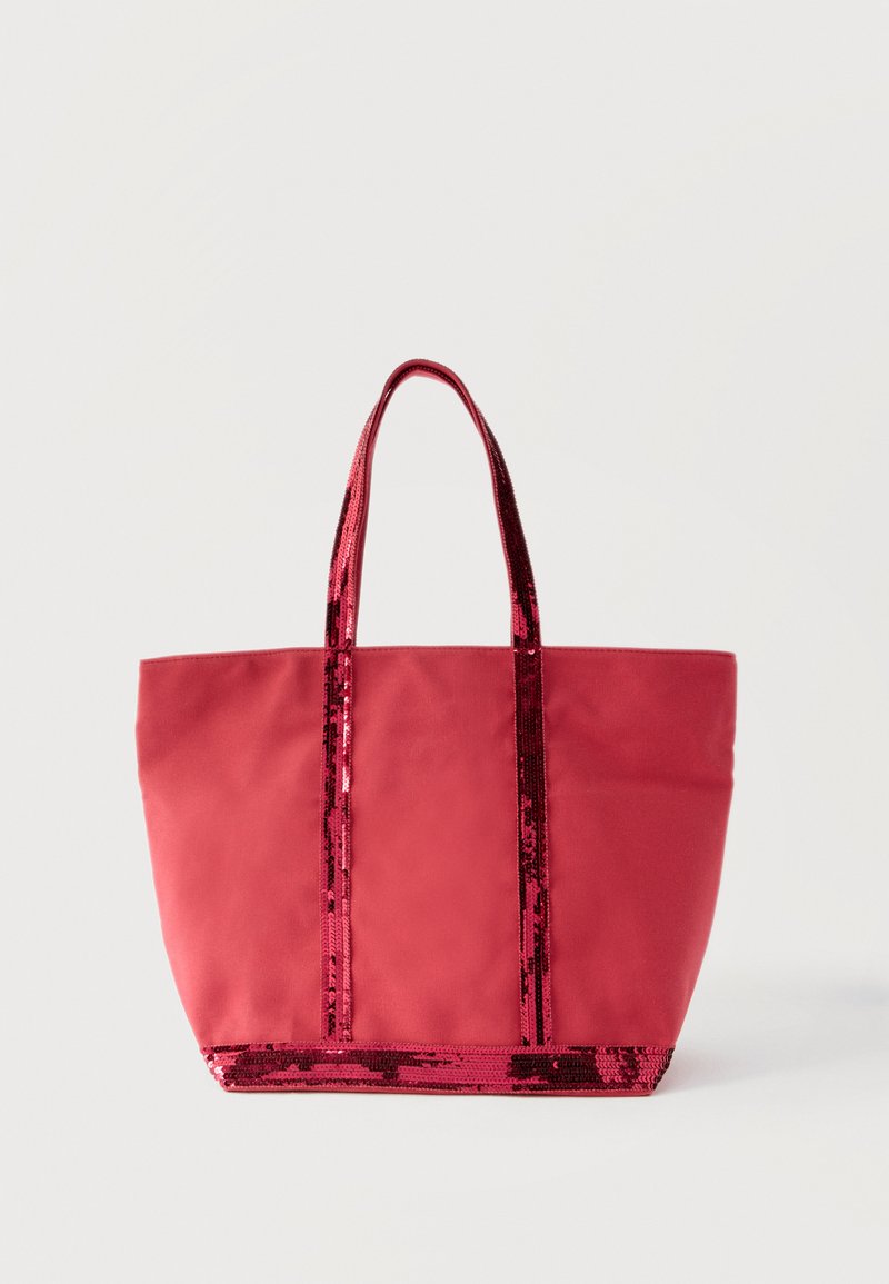 Μεγάλη κόκκινη τσάντα ώμου με δύο λαβές διακοσμημένες με παγιέτες και αντίστοιχη διακοσμητική ταινία με παγιέτες κατά μήκος της κάτω ακμής, όρθια σε λευκό φόντο.
