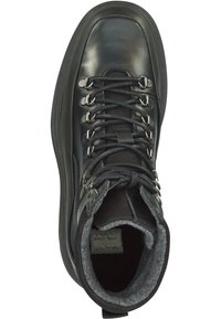 Schwarzer Wanderschuh aus glänzendem Leder und Mesh, mit grauem Wollfutter, Metallösen und strukturierten Schnürsenkeln. Auffällige, gebogene Sohle.