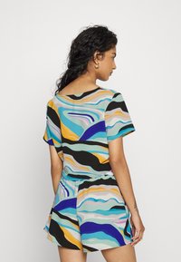 Macacão de mangas curtas com padrões de ondas multicoloridos, apresentando tons de azul, preto e laranja, feito de um tecido leve e com um corte descontraído.