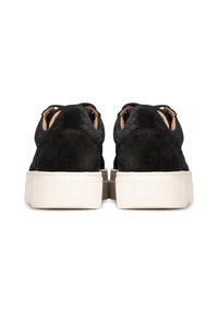 Zapatillas de ante negro con acentos texturizados, suela de goma blanca y cordones con ojales de metal. La vista trasera enfatiza la altura y la forma.