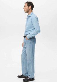 Camisa de botones azul claro, vaqueros de pierna recta azul claro, zapatos de cuero negros y cinturón negro. Diseño sencillo, textura suave, ajuste informal.