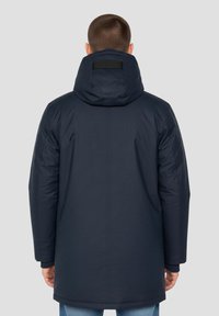 Cappotto imbottito blu navy con cappuccio, caratterizzato da una texture liscia, tasche laterali e regolazione in velcro sul retro. Design casual con taglio dritto.