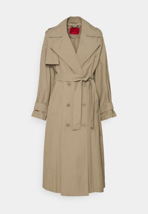 Béžový dvouřadý trenčkot se širokými klopami, páskem v pase, knoflíky na manžetách a detaily s klopovými kapsami, visící na bílém pozadí.