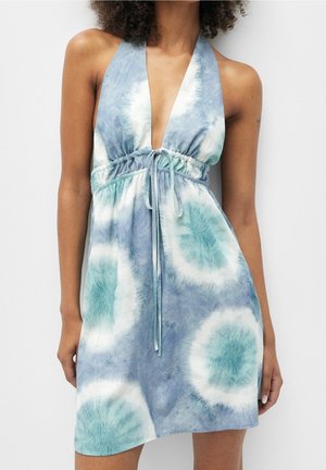 Robe dos nu avec col en V profond et ceinture à nouer, présentant des motifs circulaires tie-dye bleus et blancs sur un tissu léger.