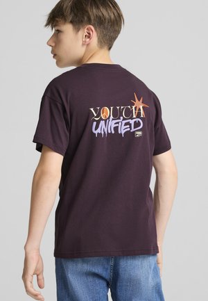 Lilla bomulds t-shirt med "YOUTH UNIFIED" i multikolor tekst på ryggen, med rund hals og korte ærmer.