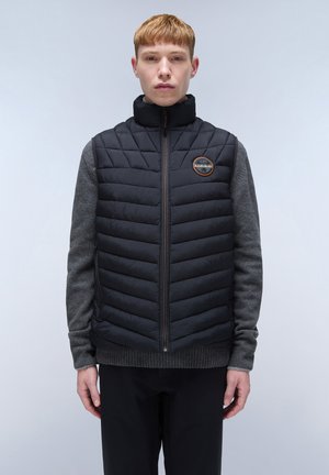 Black puffer vest with a high collar, featuring quilted texture and a gray sweater underneath. Includes a round logo on the chest.
