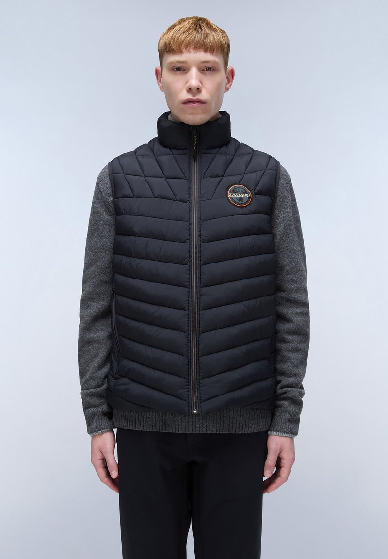 Schwarze Steppweste mit hohem Kragen, ausgestattet mit gesteppter Textur und einem grauen Pullover darunter. Enthält ein rundes Logo auf der Brust.