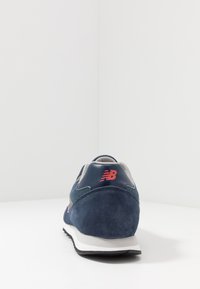 Námořnické modré tenisky s hladkým koženým a semišovým svrškem, šedými síťovinovými akcenty, bílou mezipodešví a červeným logem na patě.