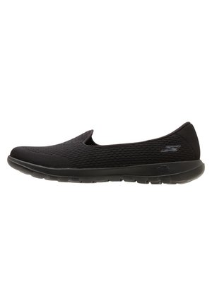 Chaussure décontractée noire sans lacets avec tige en mesh et semelle coussinée, avec un logo discret de la marque sur le côté et le talon.
