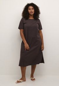Robe en coton marron foncé à manches courtes et longueur genou. Dotée d'un col rond et de fentes latérales pour une liberté de mouvement. Design uni.