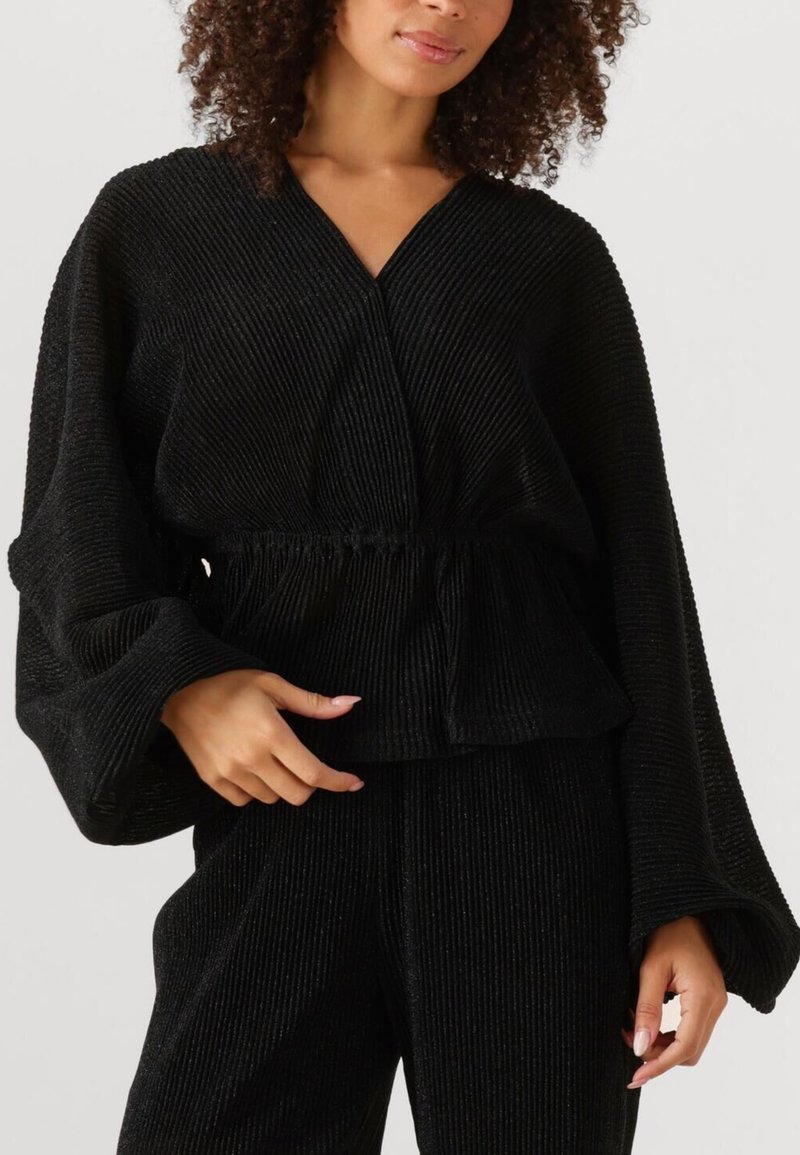 Zwarte geribbelde lange mouw top met een V-hals en elastische taille, met een gestructureerd oppervlak en brede mouwen. Gepaard met bijpassende broek.