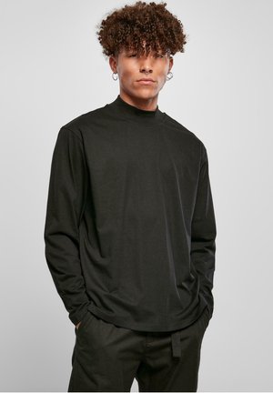 Cămașă neagră cu mâneci lungi și guler înalt, realizată dintr-un material fin. Are o croială lejeră și un design simplu, asortată cu pantaloni închiși la culoare.