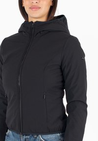 Giacca nera imbottita con chiusura a zip, cappuccio regolabile e tasche laterali. Presenta una texture liscia e un design aderente.