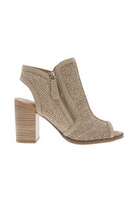 Chaussure beige à bouts ouverts et talon en bois épais, avec une fermeture éclair sur le côté et des accents cloutés le long du bord.