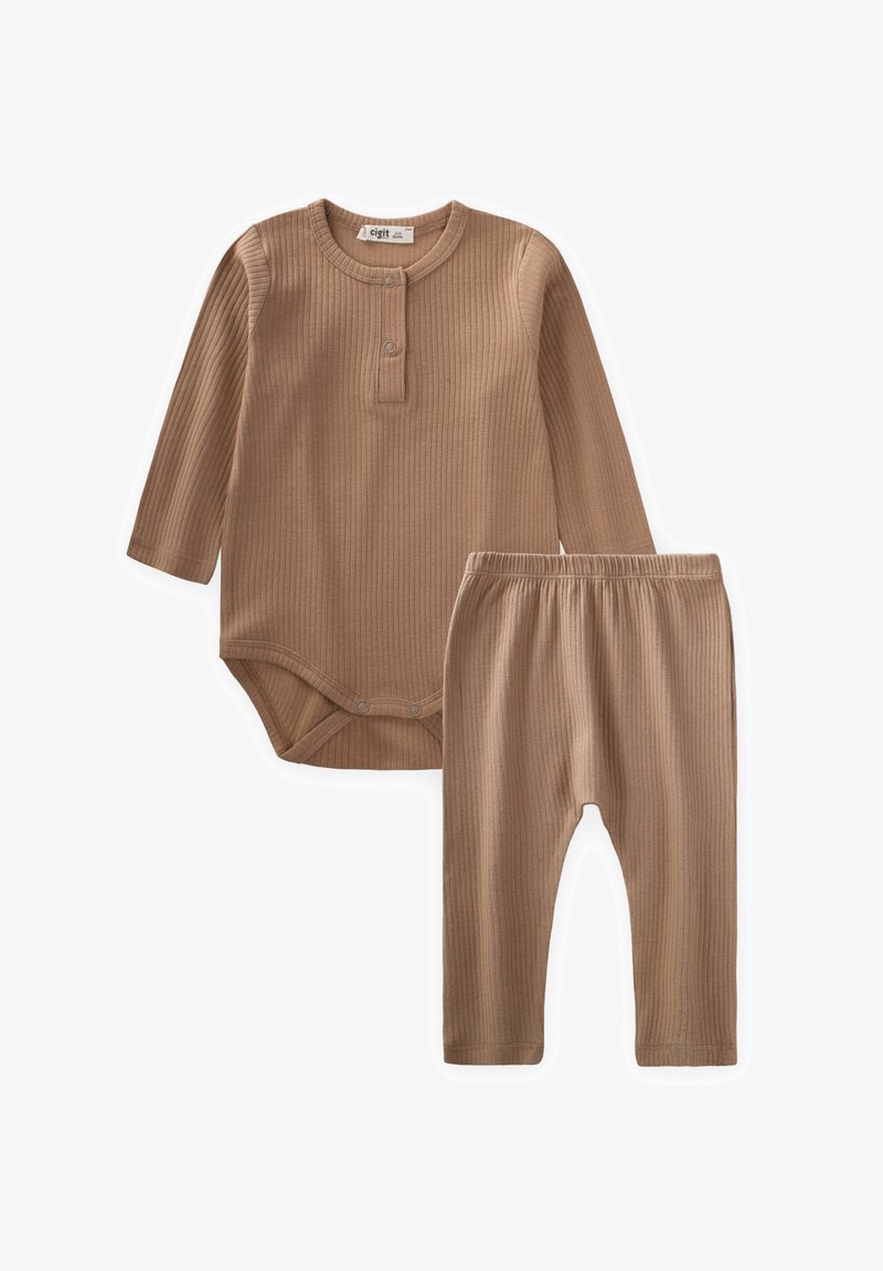 Ribota, garlaicīga bodija ar pogu aizdari un saskaņotām biksēm. Abas ir gaismas brūnā krāsā, izgatavotas no mīksta auduma ar teksturētu rakstu.