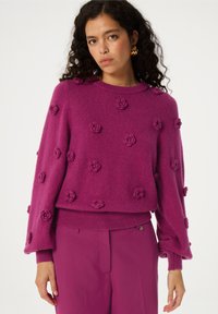 Fuchsia trui met textured bloemendetails, ronde halslijn en geribde manchetten. Zachte, fuzzy stof in een relaxte pasvorm.