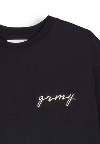 Sudadera de algodón negra con cuello redondo y logo bordado en blanco "grmy" en el lado izquierdo. Textura suave con un corte relajado.