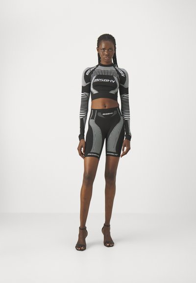 Set athletic negru format dintr-un top scurt cu mâneci lungi și pantaloni scurți asortați, cu talie înaltă, amândouă având detalii reflectorizante și accente cu logo.