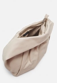 Borsa beige, dal tessuto morbido, con un intricato design annodato. Presenta una chiusura con zip e un interno foderato. Forma compatta con una silhouette unica.
